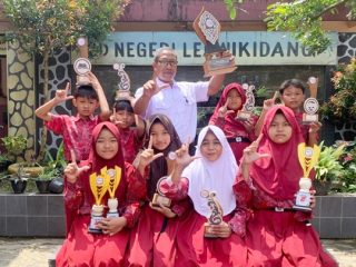 Siswa SDN Leuwikidang bersama Kepala Sekolah menunjukkan piala hasil perjuangan, usai tampil dominan dan meraih Juara Umum FLS3N 2026 di Bungursari. Dok istimewa