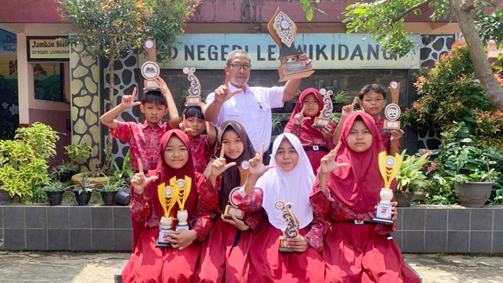 Siswa SDN Leuwikidang bersama Kepala Sekolah menunjukkan piala hasil perjuangan, usai tampil dominan dan meraih Juara Umum FLS3N 2026 di Bungursari. Dok istimewa