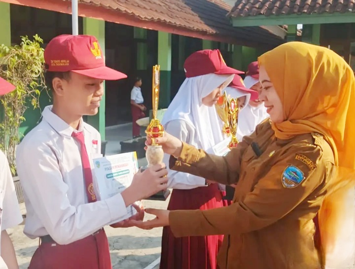 Kepala SDN Syekh Tubagus Abdullah menyerahkan piala dan penghargaan kepada siswa sebagai bentuk apresiasi atas prestasi yang telah diraih. Foto Dok. Istimewa.