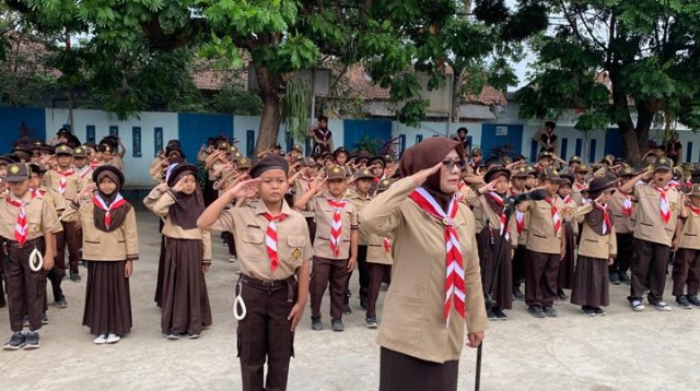 Mabigus SDN 2 Siluman, Iis Suhartini, S.Pd., memimpin penghormatan dalam upacara HUT Gerakan Pramuka ke-65 bersama ratusan anggota Pramuka Siaga dan Penggalang, Jumat (14/8/2026). Foto. Dok. Asep M