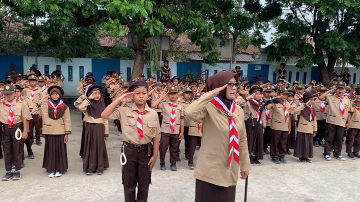 Mabigus SDN 2 Siluman, Iis Suhartini, S.Pd., memimpin penghormatan dalam upacara HUT Gerakan Pramuka ke-65 bersama ratusan anggota Pramuka Siaga dan Penggalang, Jumat (14/8/2026). Foto. Dok. Asep M